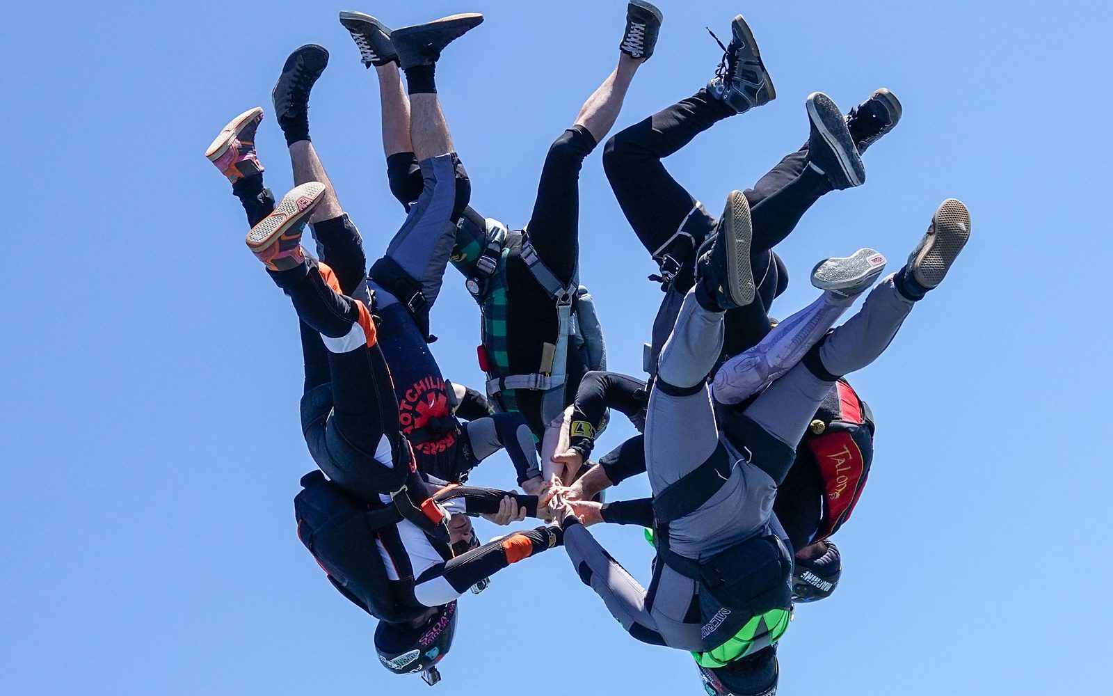 A head-down freefly formation gripped up against deep blue sky
