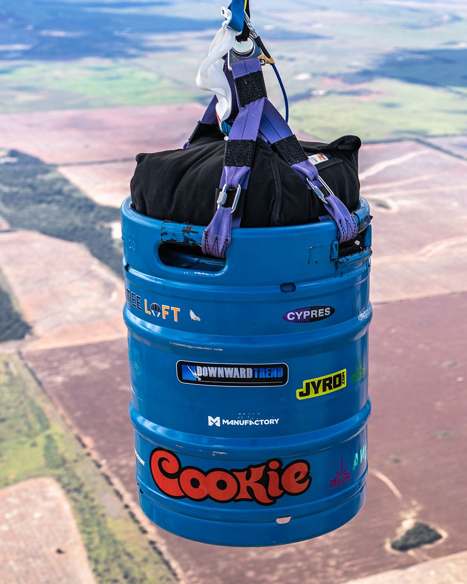 A skydiver flying alongside a branded beer keg dropped from the aircraft