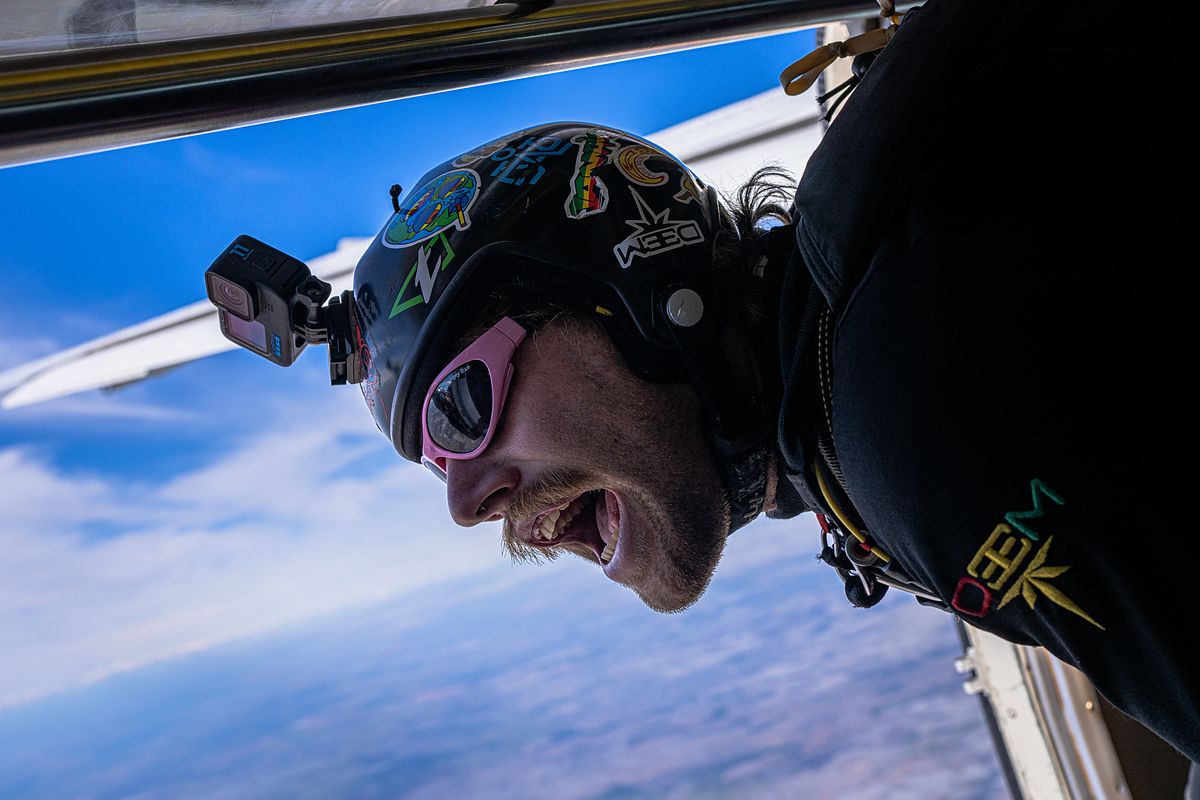 A grinning skydiver in freefall beside the aircraft wing