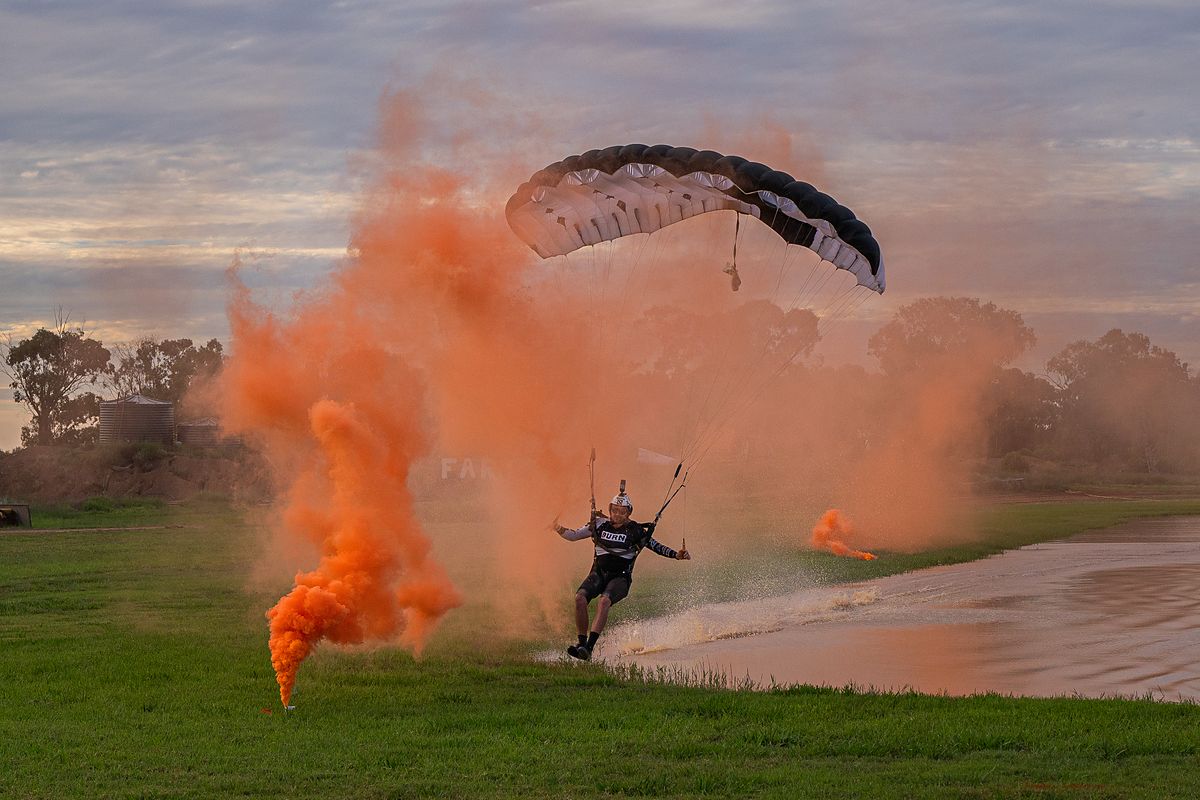 A canopy pilot landing through a wall of orange smoke