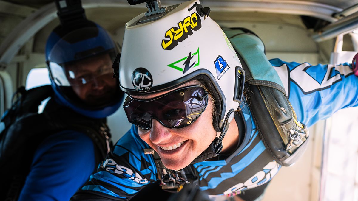 Two skydivers in helmets and goggles grinning in the aircraft before exit