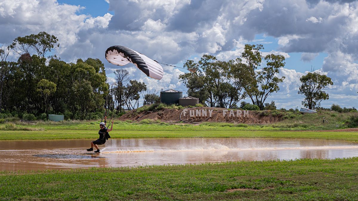 A canopy pilot swooping across the pond at the drop zone