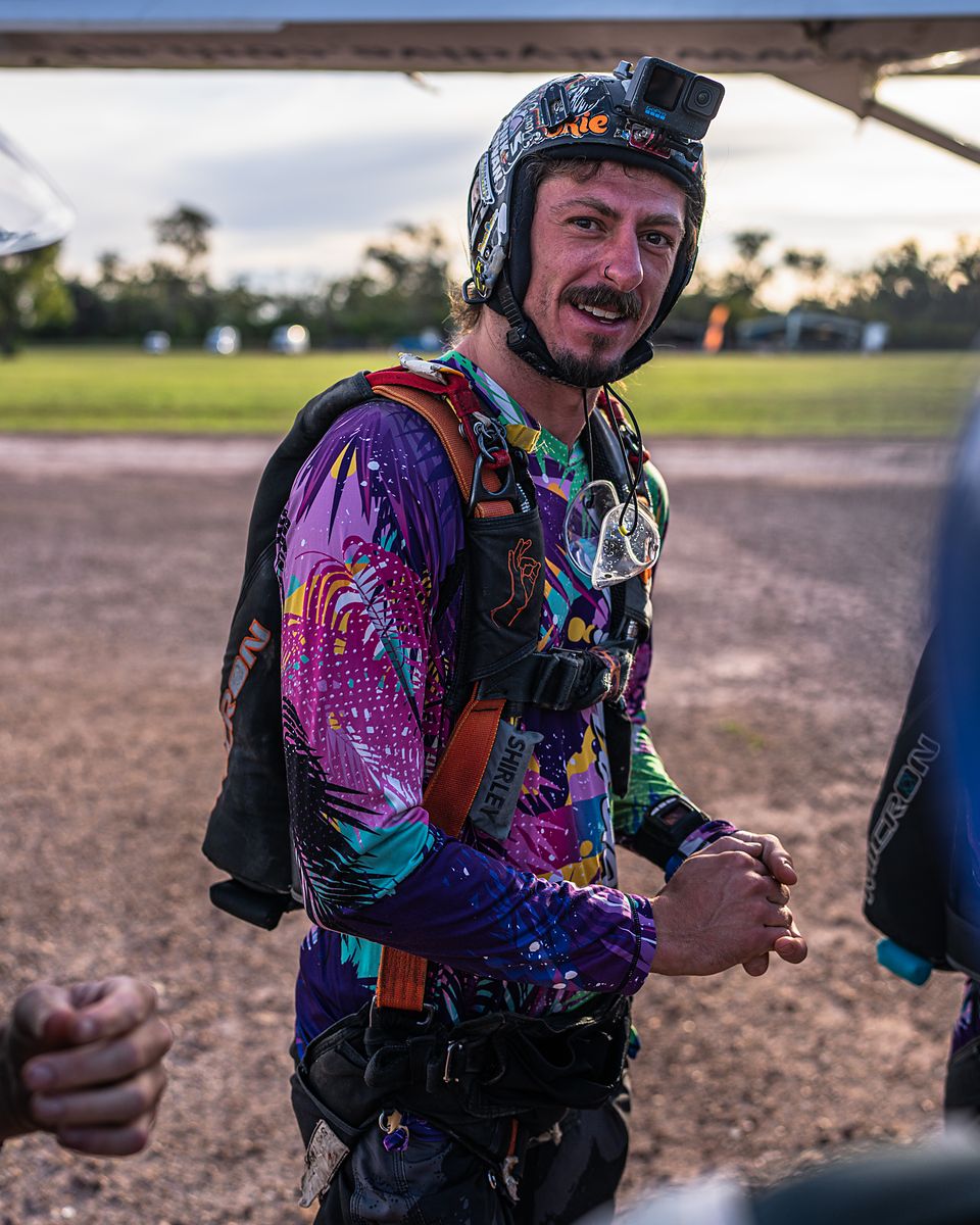 A skydiver on the ground in a bright patterned jumpsuit