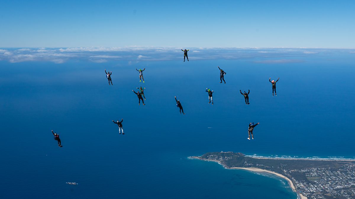 Canopies and freefallers scattered high above a coastal town
