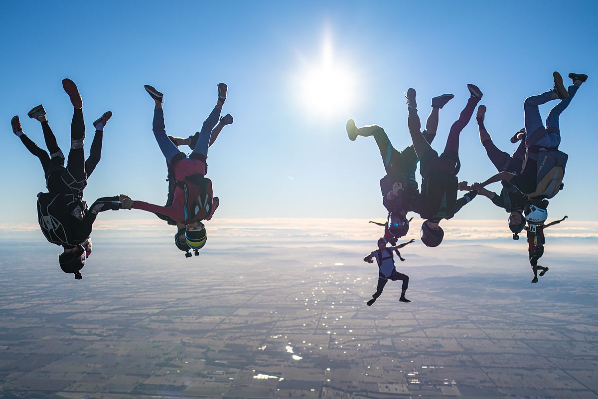 A freefall formation with the sun flaring behind it above cloud