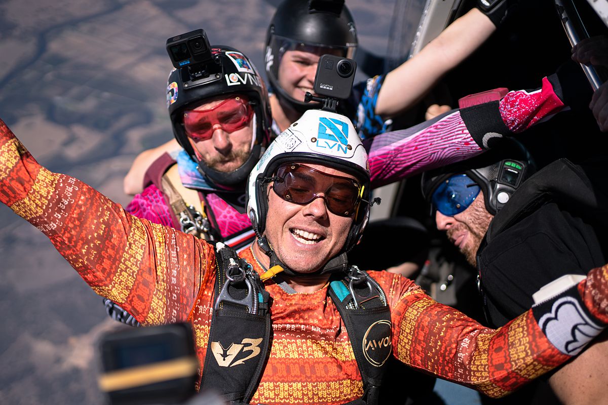 Skydivers packed into the aircraft grinning on the way to altitude
