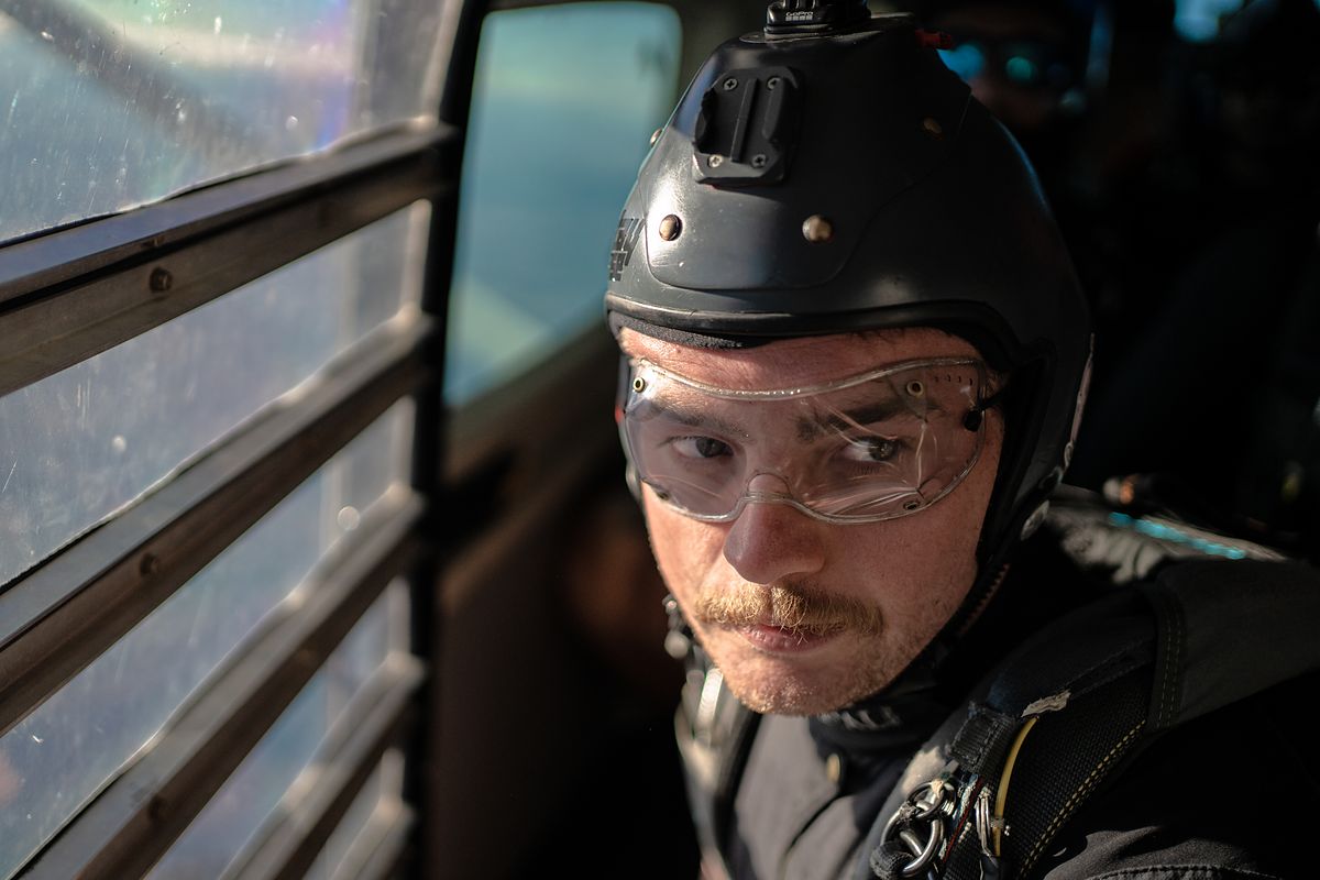 A skydiver in goggles and helmet waiting in the aircraft