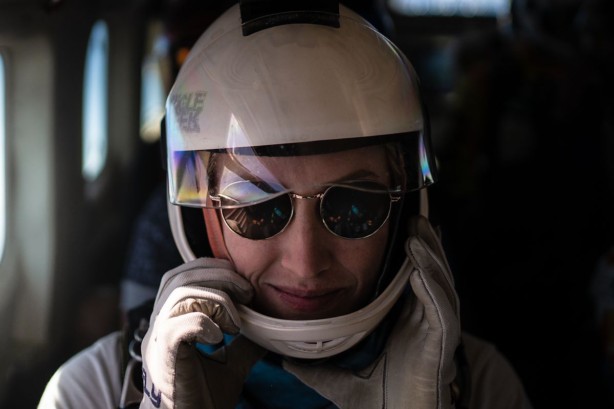 A skydiver in an open-face helmet and sunglasses by the door