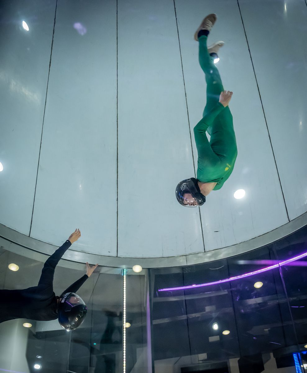 A flyer in a green suit inverted in the tunnel chamber
