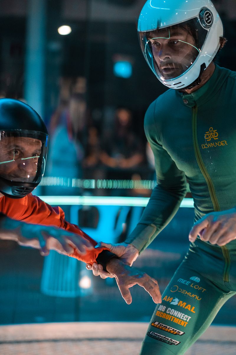 Mason coaching a flyer in the tunnel, guiding their arm mid-flight