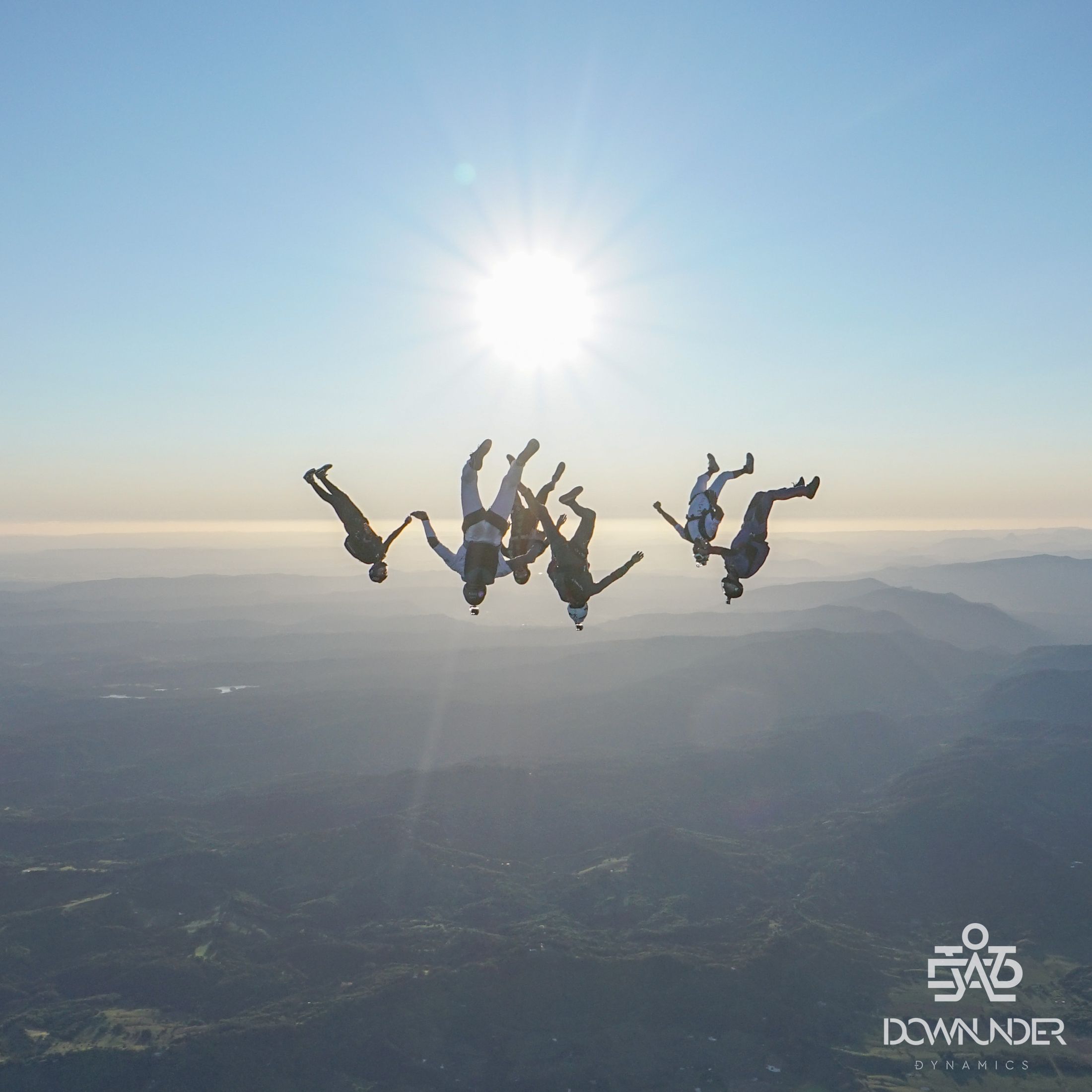 A freefly group silhouetted against the sun over the range