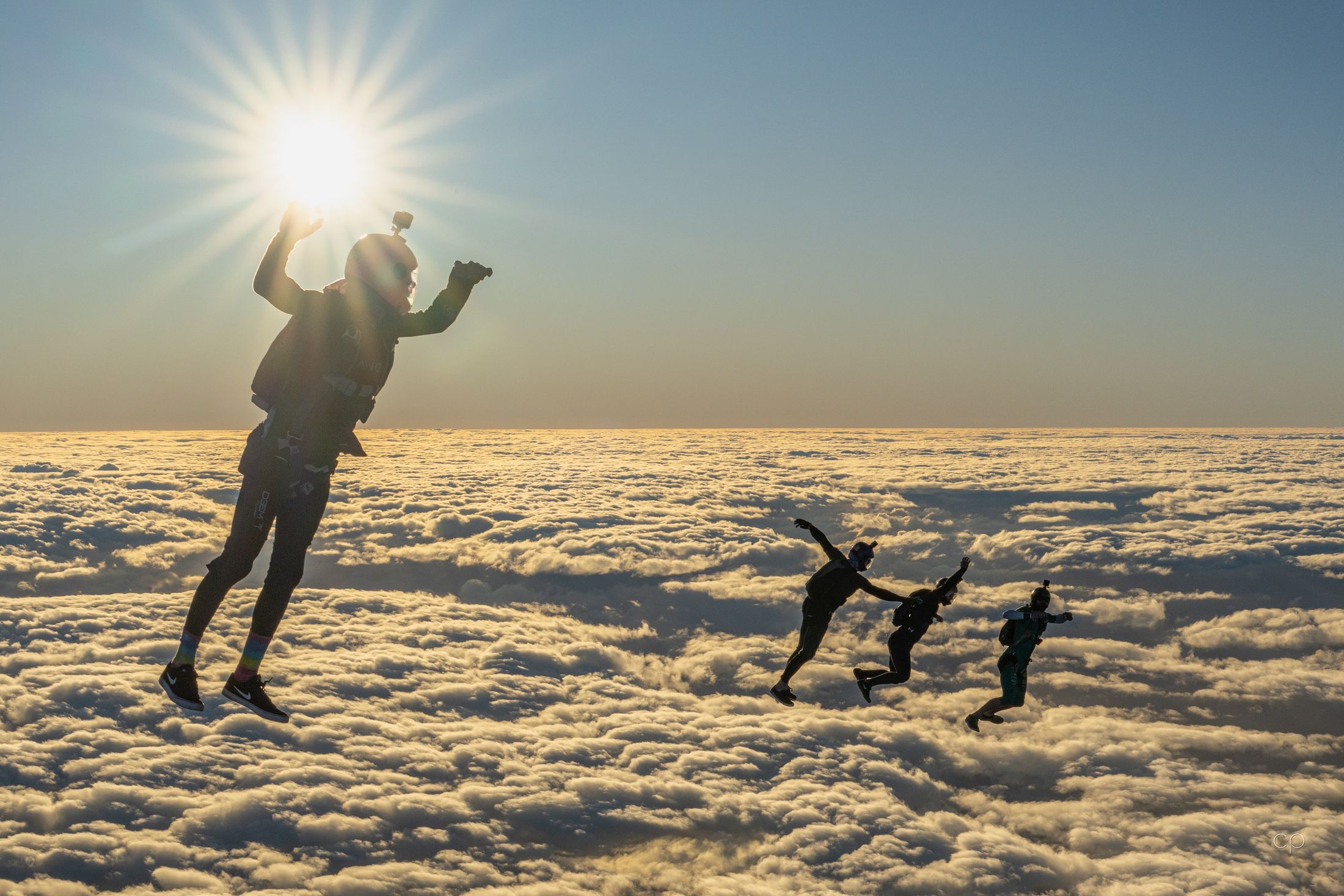 Head-up flyers above a sea of cloud, sun behind